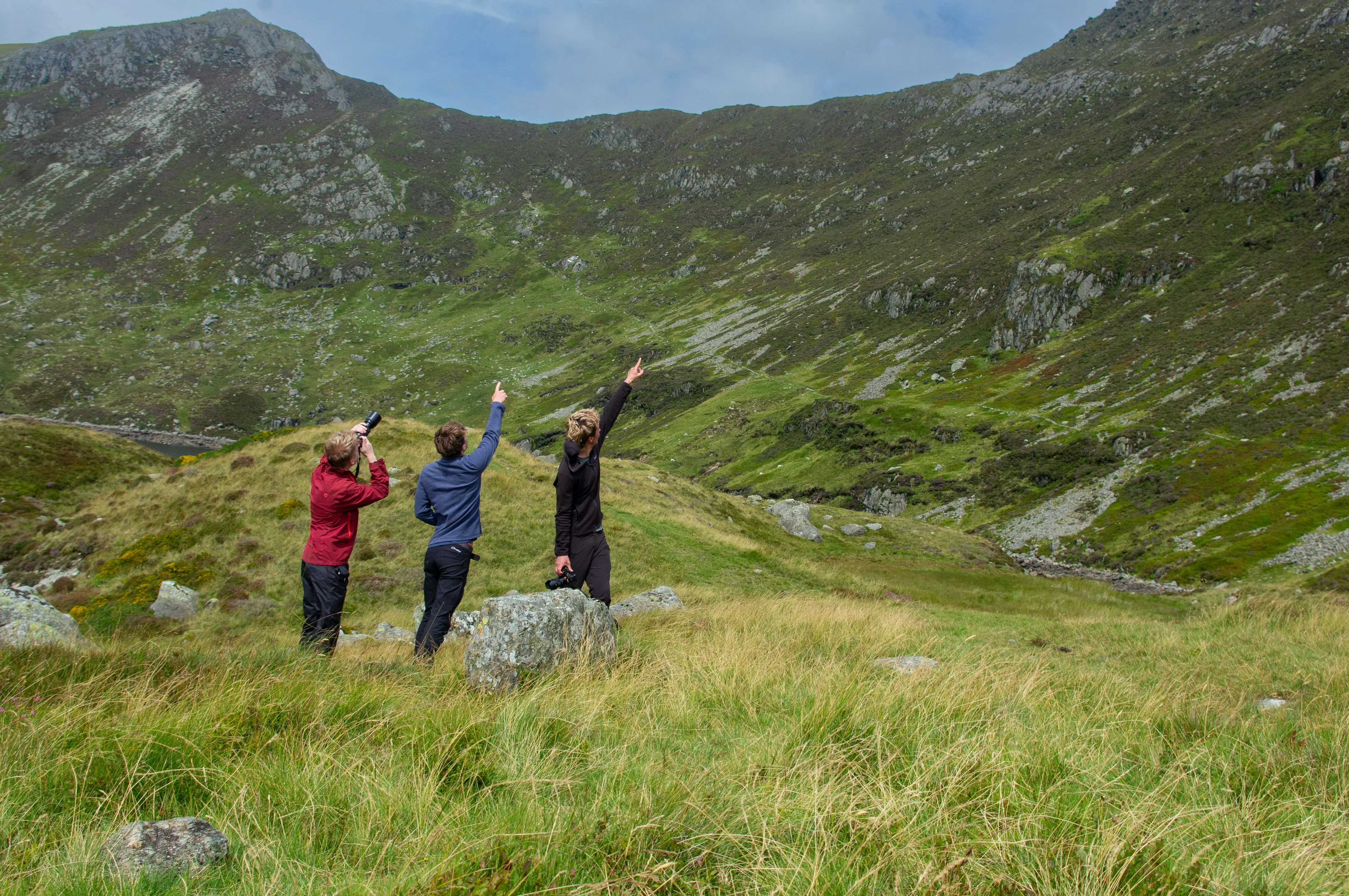 3 men poinging up a mountain
