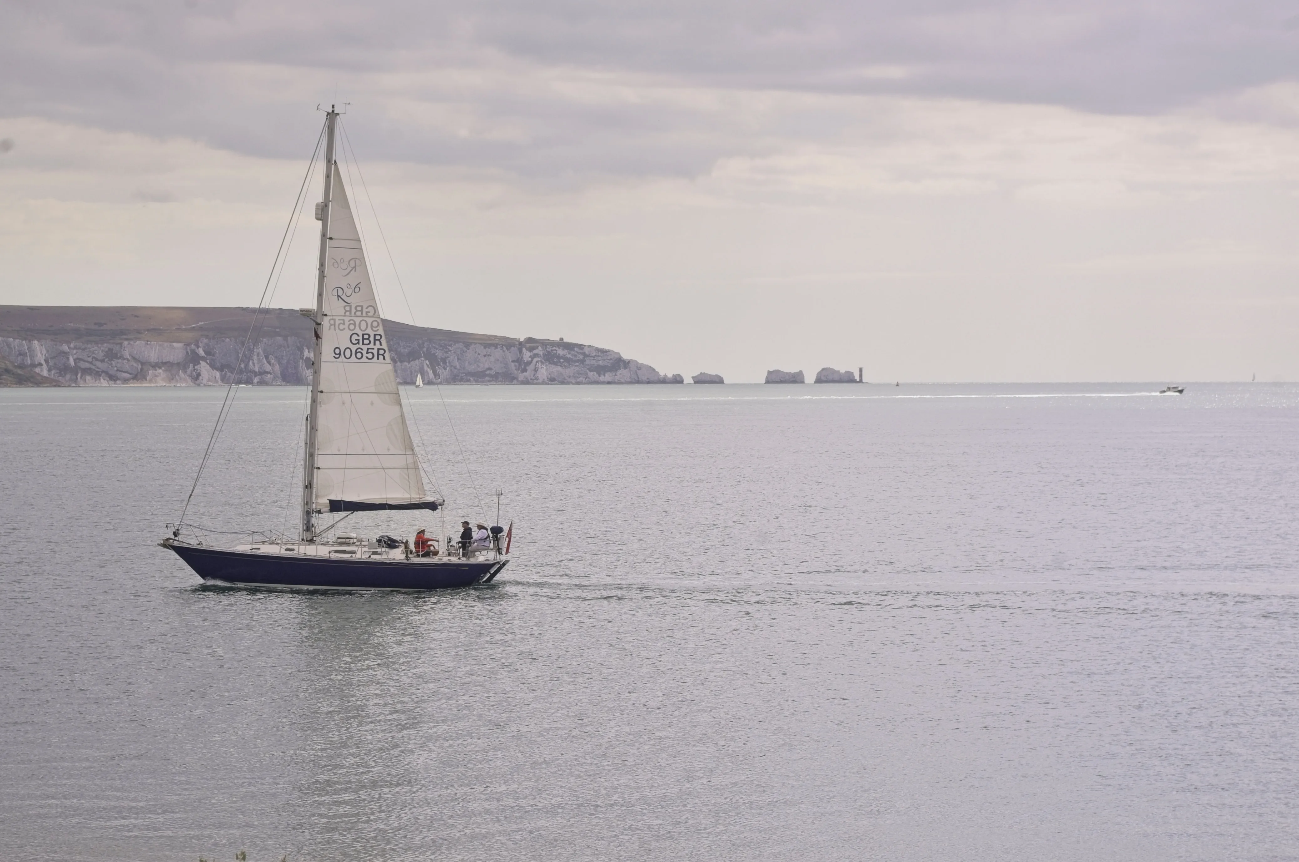 A boat on the sea in front of the Isle of Wight and the Isle of Wight Needles