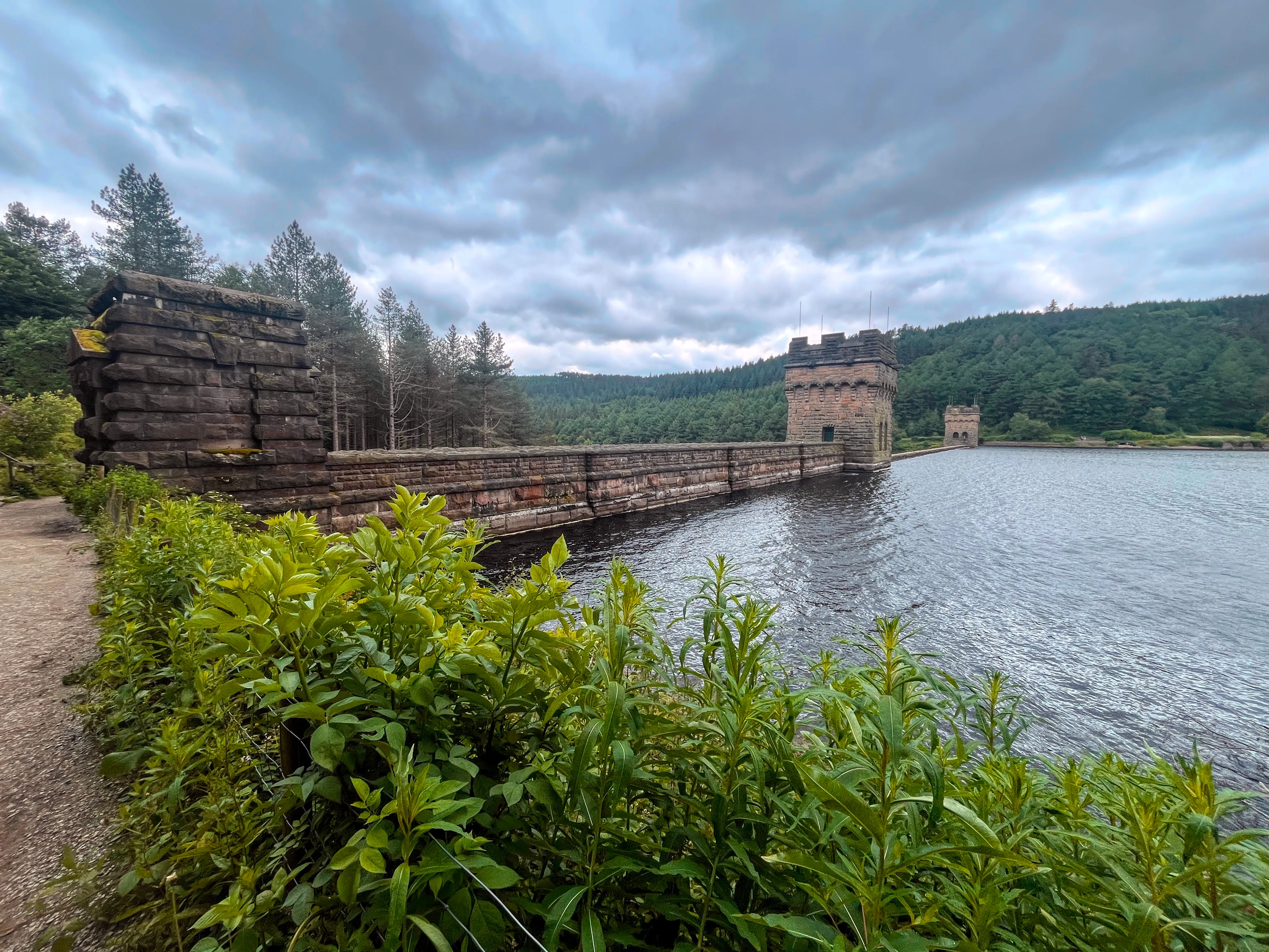 A photo of three towers with a wall between them holding back water