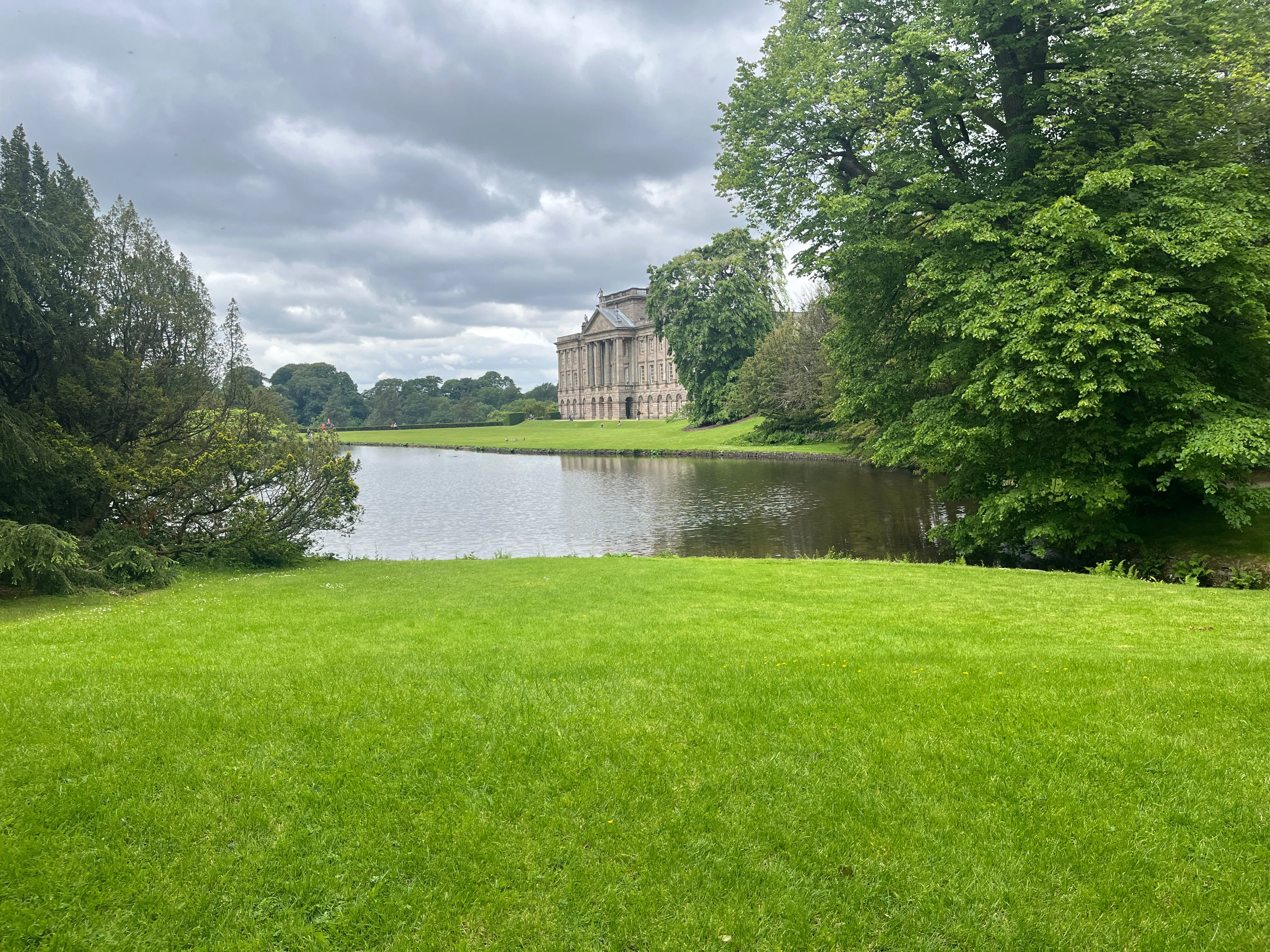 A view of a lake with a large country house on the other side