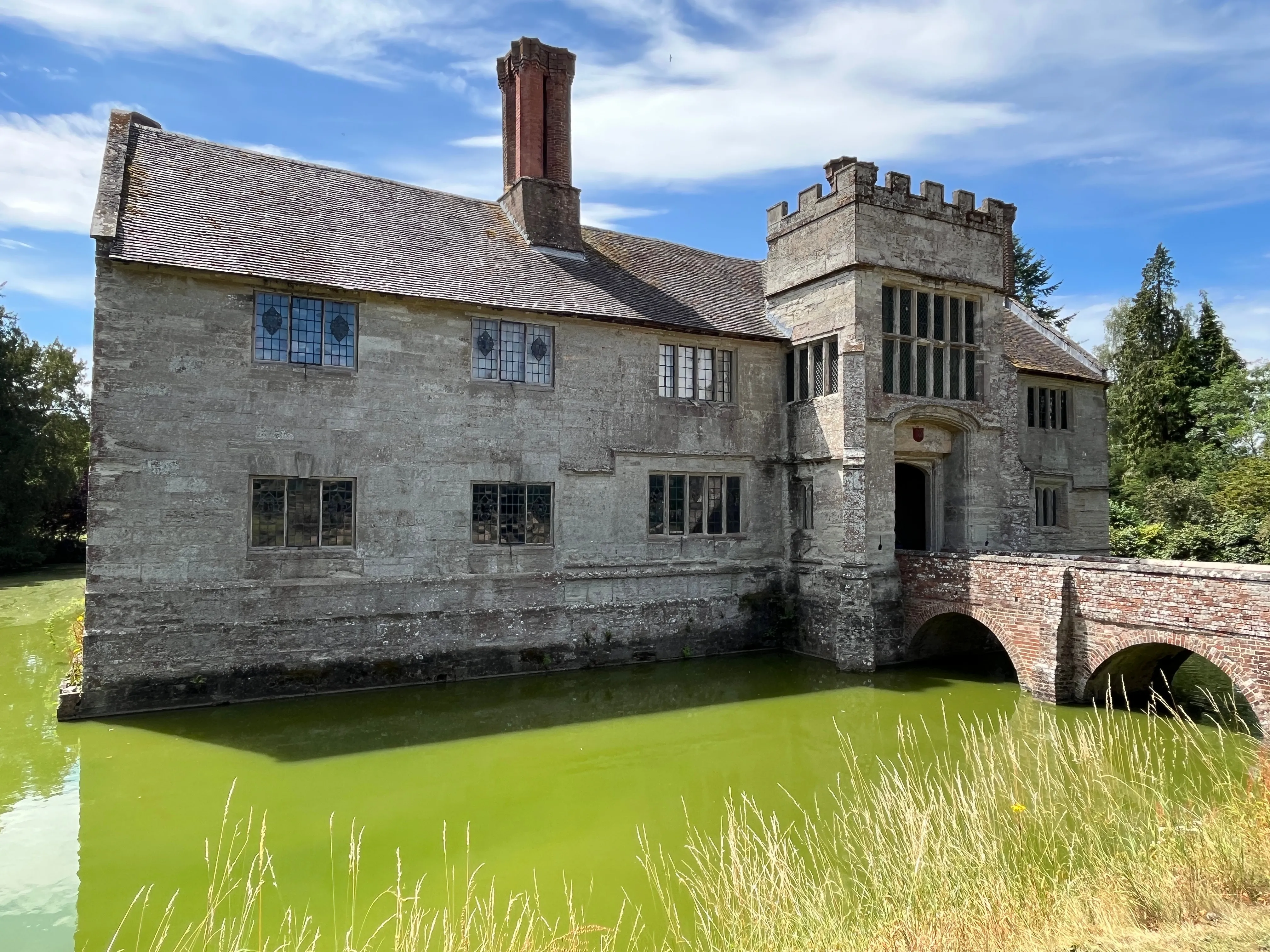 A large stone house with moat around it and bridge across