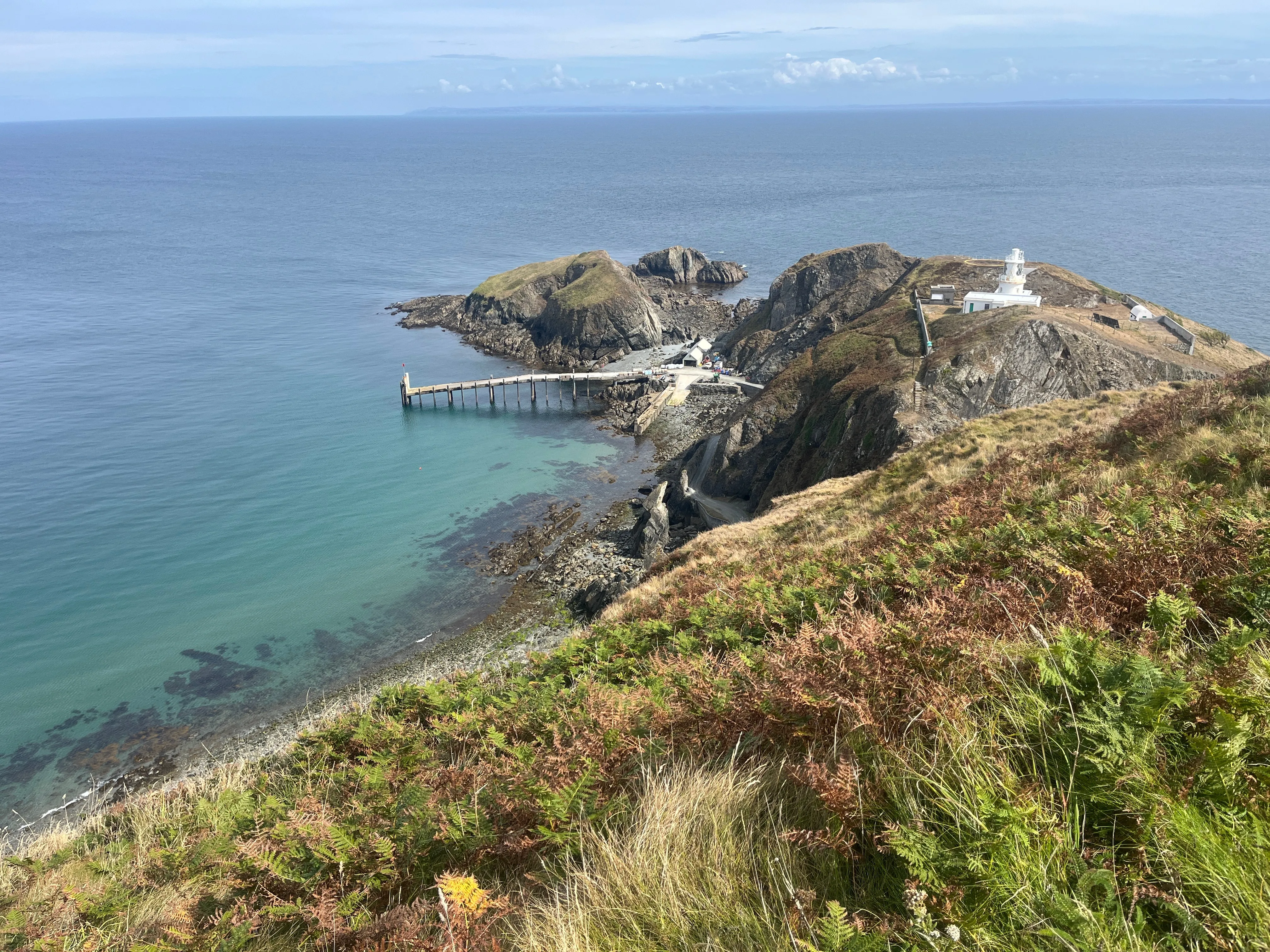 A jetty going out to sea at the bottom of a large hill